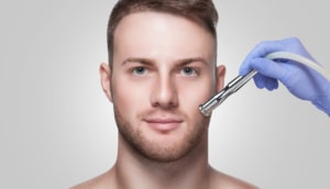 hand in blue glove placing microdermabrasion on man’s face