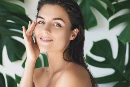beautiful woman with perfect smooth skin in tropical leaves