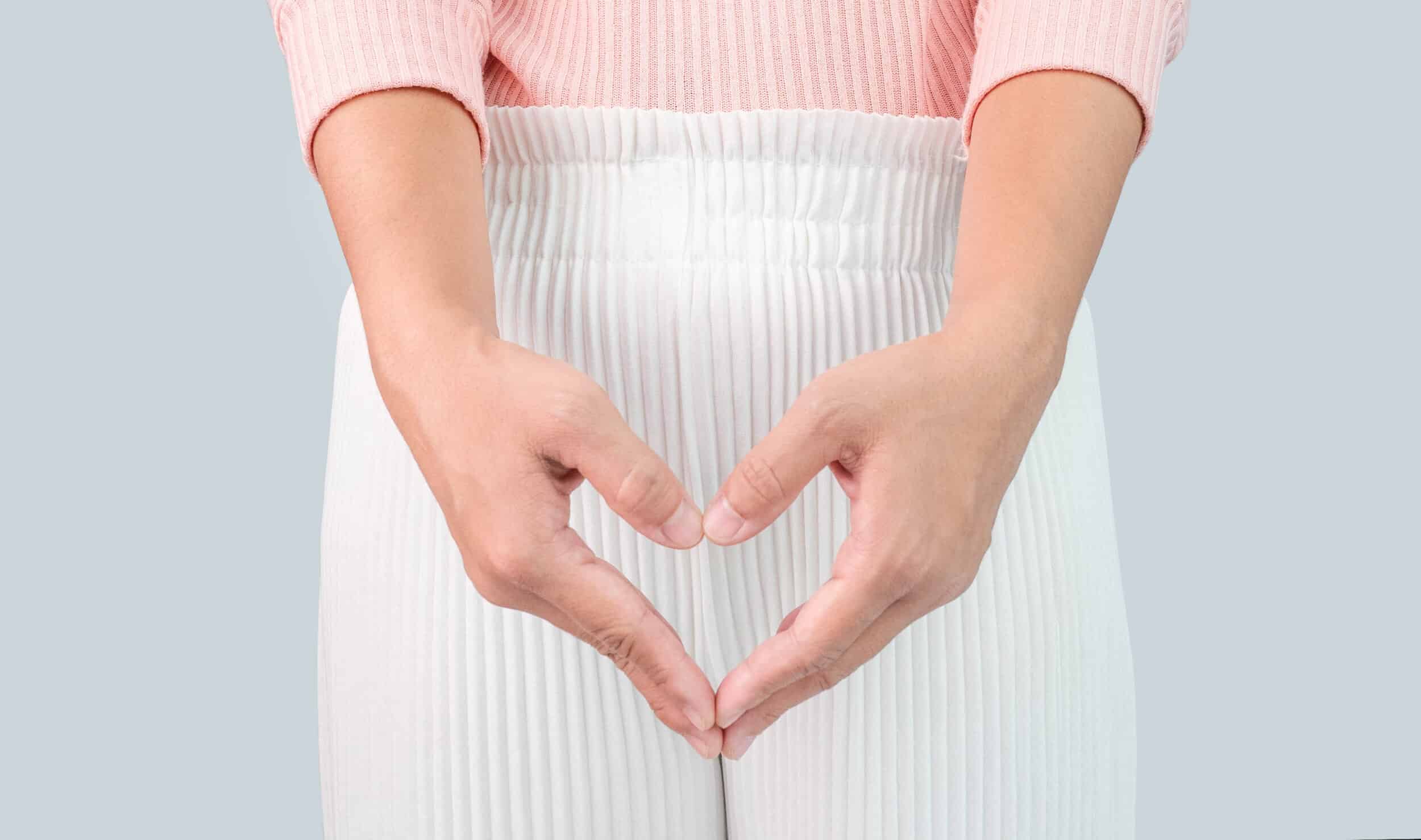 Fully clothed woman holding heart shape with hands over her feminine area