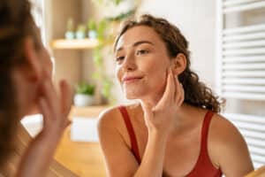 Woman examining her skin in the mirror and considering IPL photofacial treatment