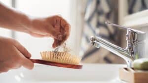 Woman holding hands around her midsection indicating a healthy gut Woman holding hair in a comb due to hair loss.