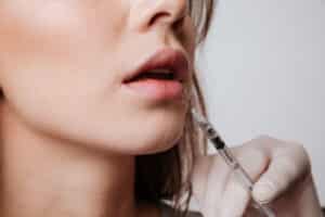 Woman holding hands around her midsection indicating a healthy gut Close-up shot of woman getting Restylane® lip fillers